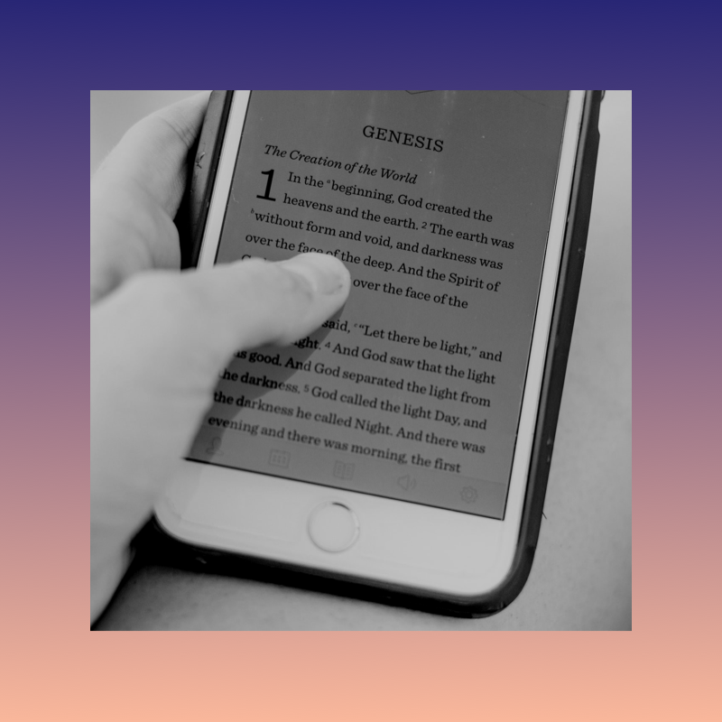 A hand holding a phone displaying the book of Genesis